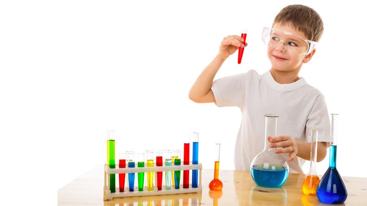 Young boy behind a chemistry set holding a test tube.